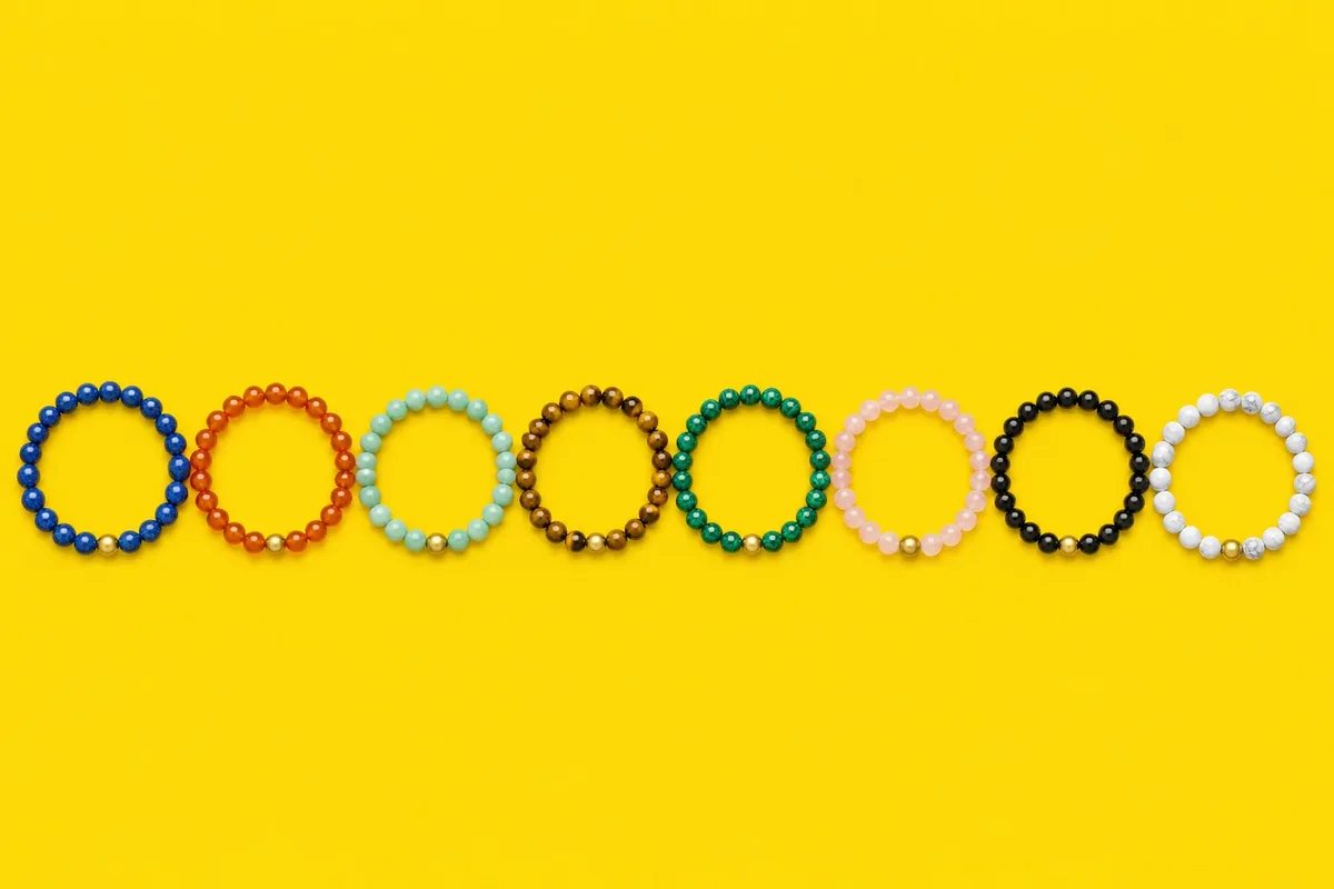 Strip of paper wrapped around a wrist beside a ruler and three stone bracelets
